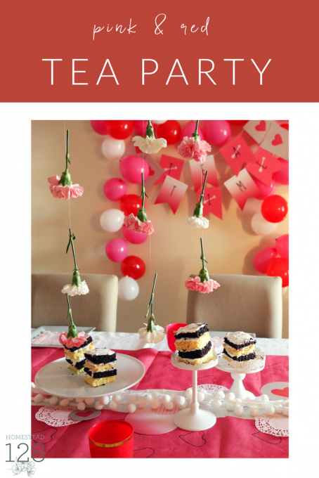 A pink and red colored tea party for little girls with flowers, cake, hearts and balloons.